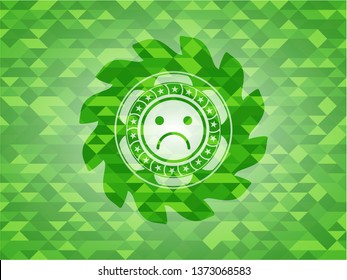 sad face icon inside realistic green mosaic emblem