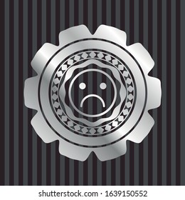 sad face icon inside silvery emblem or badge