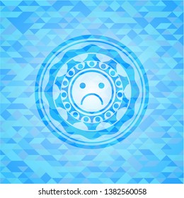 sad face icon inside sky blue emblem with triangle mosaic background
