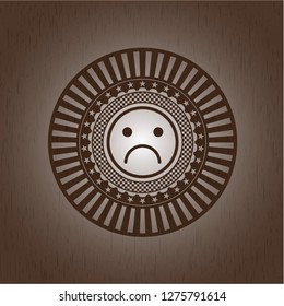 sad face icon inside wood emblem