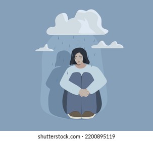 A sad girl with depression sits under clouds and rain. Lonely woman. The concept of depression, melancholy, pessimism, loneliness.