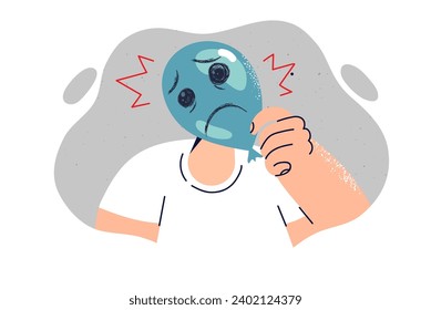 Sad grimace is drawn on balloon and hand of man hiding emotions due to psychological crisis and stress. Concept of mental problems causing stress and lack of motivation for personal development