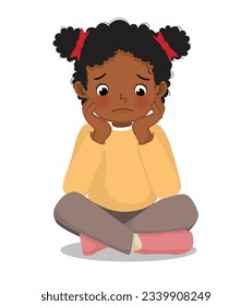 Sad little African girl sitting on the floor with her chin resting on her hands