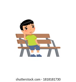 Sad Little Asian Boy. Unhappy Child Sitting On Bench. Lonely Boy Is Bored In The Playground.