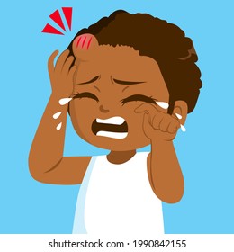 Sad little black girl crying in pain with bump bruise on forehead