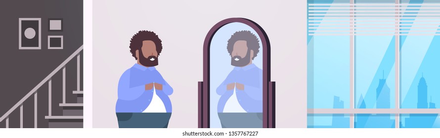 sad overweight man looking at himself reflection in mirror african american over size guy buttoning shirt unhealthy lifestyle obesity concept modern apartment interior flat portrait horizontal