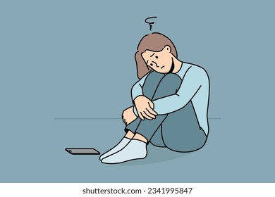 Sad woman is waiting for phone call, sitting on floor and suffering from loneliness or lack of friends. Sad girl sadly awaits arrival of sms message about replenishing bank account