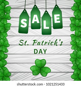 Sale poster of Saint Patrick's day with emerald shamrocks on light wooden background and hanging green tags. Vector illustration