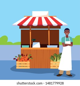 salesman with stall kiosk of store vegetables