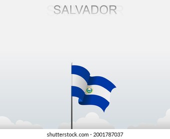 The Salvadoran flag flutters on a pole that stands tall under a white sky