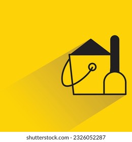 sand bucket and shovel with shadow on yellow background