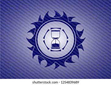 sand clock icon inside badge with denim background