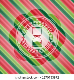 sand clock icon inside christmas colors badge.