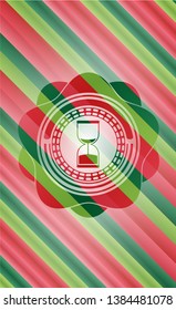 sand clock icon inside christmas colors emblem.