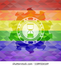 sand clock icon inside emblem on mosaic background with the colors of the LGBT flag