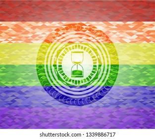 sand clock icon inside emblem on mosaic background with the colors of the LGBT flag
