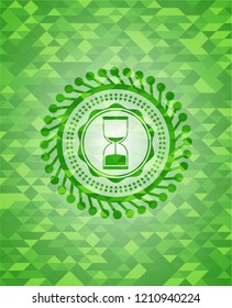 sand clock icon inside green emblem. Mosaic background