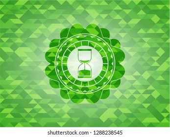 sand clock icon inside green mosaic emblem