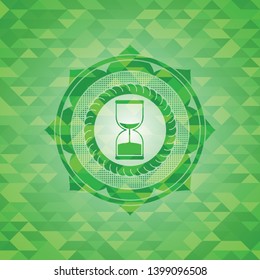 sand clock icon inside green emblem with triangle mosaic background