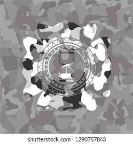 sand clock icon inside grey camouflage emblem