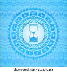 sand clock icon inside light blue water wave emblem background.