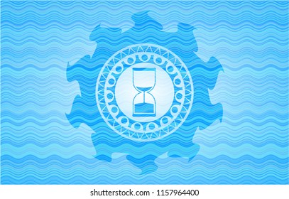 sand clock icon inside sky blue water wave emblem.