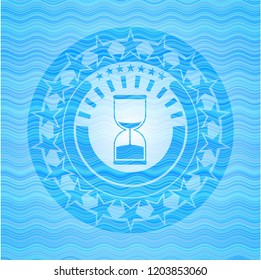 sand clock icon inside water representation emblem.