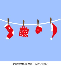 Santa Claus accessories hang on clothespins. Cap with gift sock and mittens