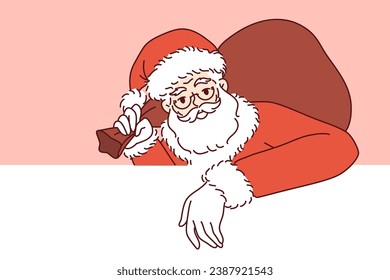 Santa claus with bag of christmas gifts leans on white banner and looks at screen inviting to new year party. Santa claus with gray beard and mustache congratulates on winter holidays