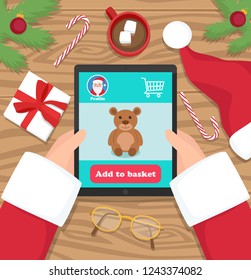 Santa Claus buying gifts for kids on his tablet - flat design vector illustration. Santa is holding his tablet on wooden desk.