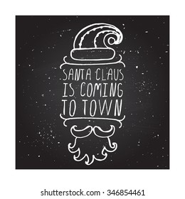 Santa Claus is coming to town - Christmas typographic element. Hand sketched graphic vector element with text, hat, mustache and beard of Santa Claus on chalkboard background.