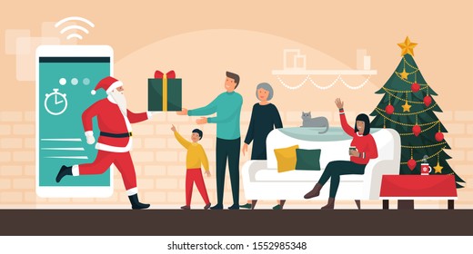 Santa Claus delivering gifts at home, he is stepping out from a smartphone and giving the present to a happy family at Christmas