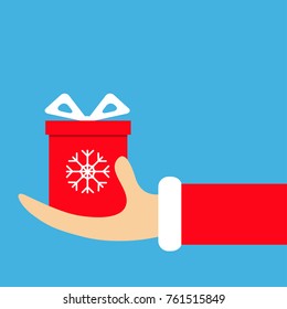 Santa Claus hand holding gift box with bow snow flake. Merry Christmas. Red costume fur. Giving giftbox present. Cute cartoon kawaii funny father character. Blue background Greeting card Flat. Vector