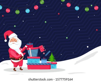 Santa Claus Presenting Gift Boxes with Xmas Tree and Colorful Baubles Garland Decorated on Blue Wavy Strip and Snowy Background.
