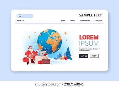 santa claus in red costume sitting near world map and gift boxes using laptop happy new year merry christmas holidays celebration