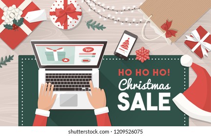 Santa ordering Christmas gifts online and connecting with his laptop: Christmas holiday sale and online shopping concept