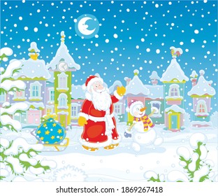 Santa and Snowman carrying a magic bag of winter holiday gifts on a toy sledge down a snowy street with colorful houses of a small pretty town on the night before Christmas