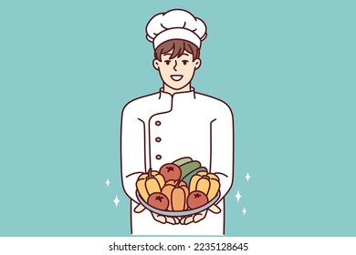 Un hombre satisfecho con la ropa de su chef sostiene platos con verduras frescas en la mano que ofrecen para hacer ensalada de verduras. Cocina de restaurante con ingredientes para preparar comida vegetariana. Diseño vectorial plano