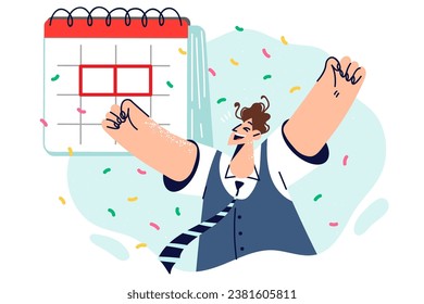 Satisfied man near calendar rejoices at approaching holiday and proudly raises hands up as sign of success. Business guy achieved career success by meeting deadlines and improving work productivity