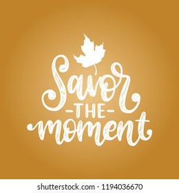 Savor The Moment, hand lettering. Inspirational quote. Vector illustration with maple leaf. Autumn holidays background.
