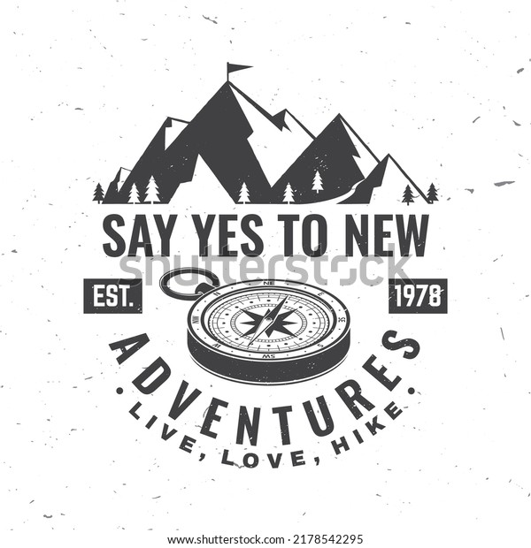 Say yes to new adventure. Live, love, hike. Vector\
illustration. Concept for shirt or logo, print, stamp or tee.\
Vintage typography design with compass and mountain silhouette.\
Camping quote.