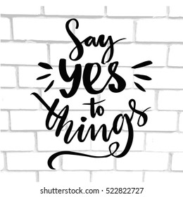 Say yes to things. Positive quote, brush typography at white brick wall texture.