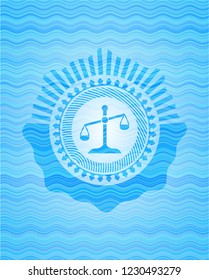 scale icon inside sky blue water wave emblem.