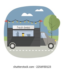 Scene with coffee truck, decorated with lights, standing on the road in a park or somewhere in the nature. 