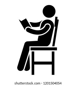 School boy sitting on desk chair and reading book