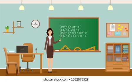 School classroom with chalkboard, clock and teacher's desk. TEacher staing in class room interior.