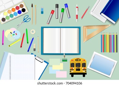 School supplies are lying around the open book on the green background. Free place for your text is in the open book.