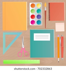 School supplies on a wooden work table top view.