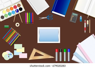 School supplies, tablet with empty screen and tools are lying on a brown wooden table. 