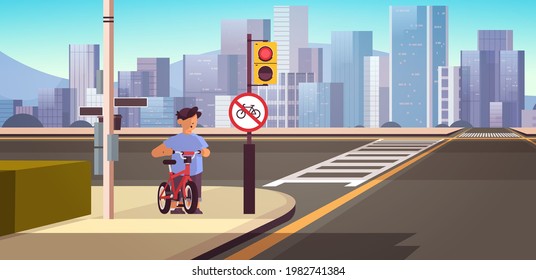 schoolboy with bicycle standing near red round kike ban sign road safety concept horizontal cityscape background